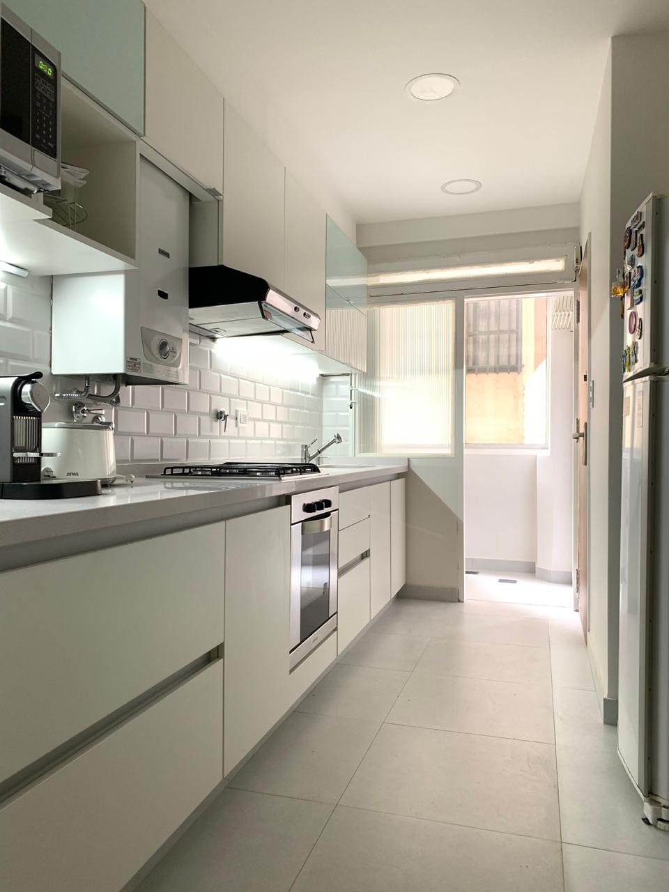 cocina pequeña blanca con mesa de cuarzo combinando con pared de ladrillos diseñada por Plakart