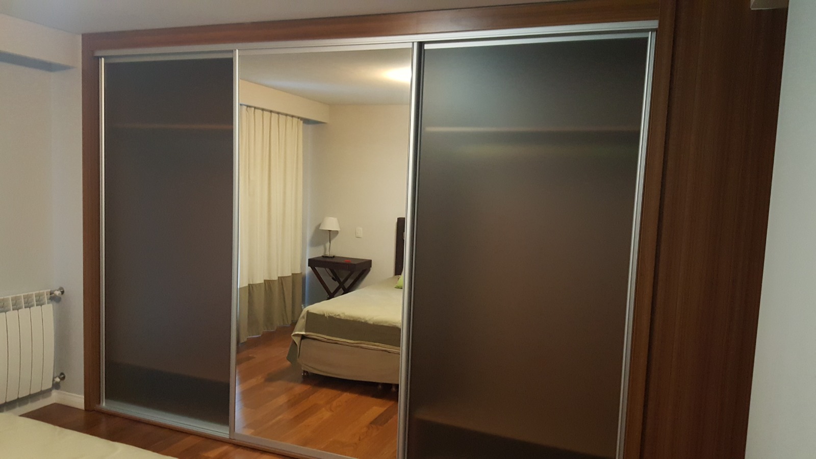 Placard de madera con espejo en una habitacion elegante con cortinas y lampara de techo